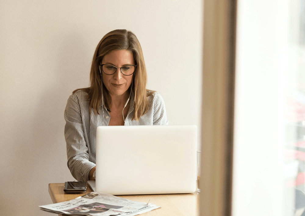 Frau sitzt mit Kopfhörern vor einem Laptop 